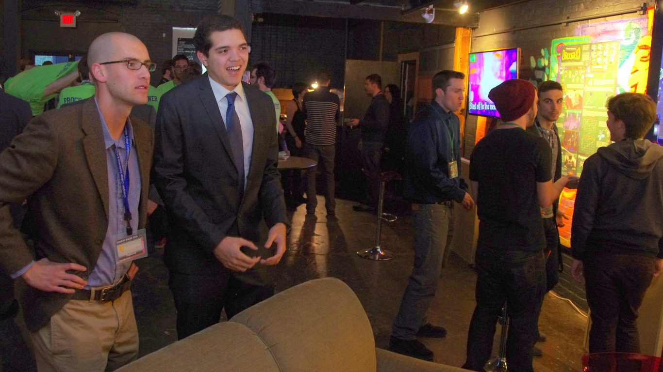 2 men in suits playing a video game and smiling